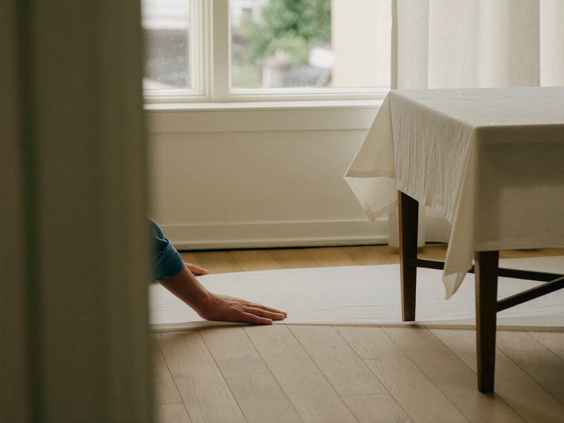 A dust sheet being laid over the floor beside a covered table before work starts