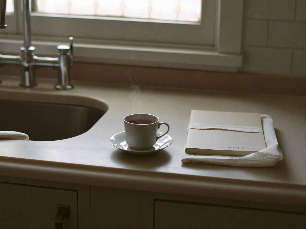 A cup of tea on a quiet kitchen counter beside a folded cloth